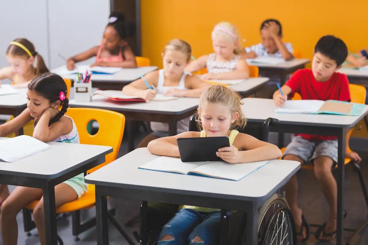 A diverse group of elementary-aged students stand in front of a blackboard, demonstrating an inclusive classroom.