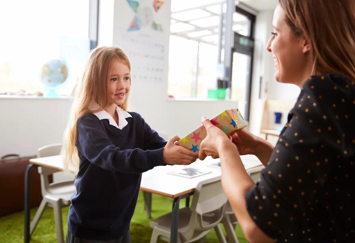 A young girl shows appreciation by giving her teacher a gift.
