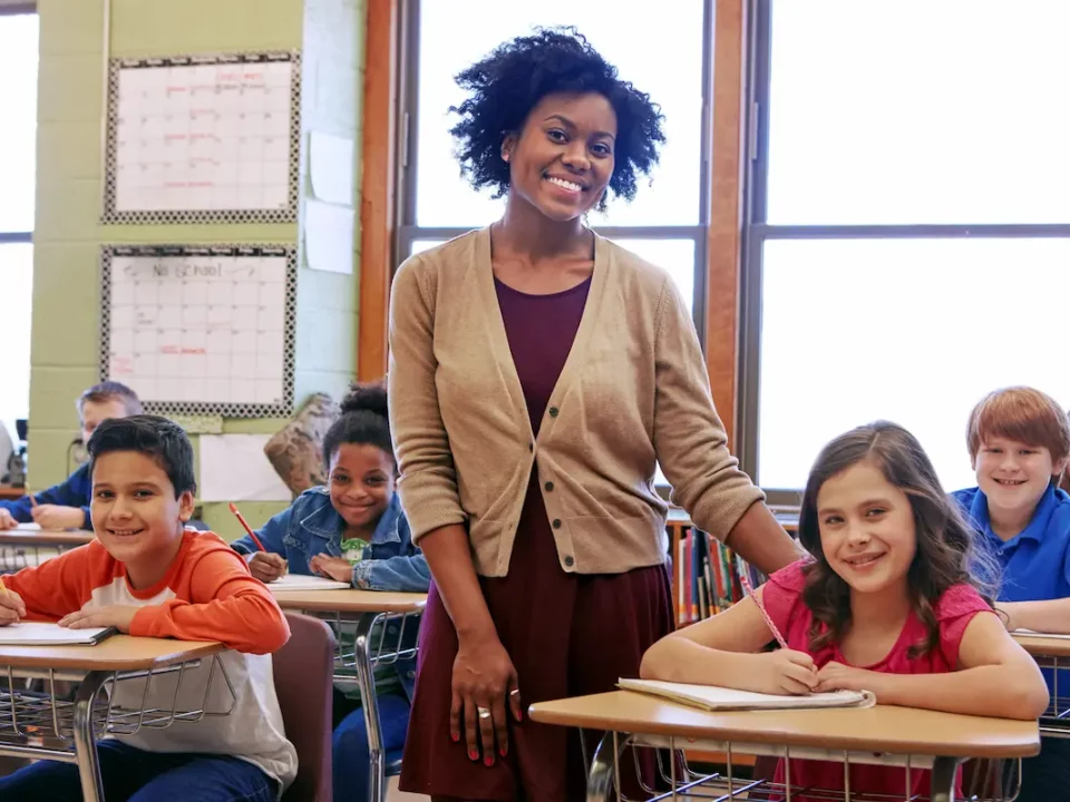 A teacher stands in her classroom smiling during teacher appreciation month.