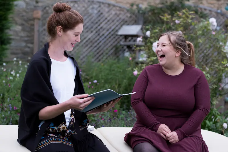 Two female teachers laughing together and avoiding teacher burnout.