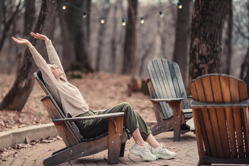Woman relaxes in a wooded area to try to stave off teacher burnout.