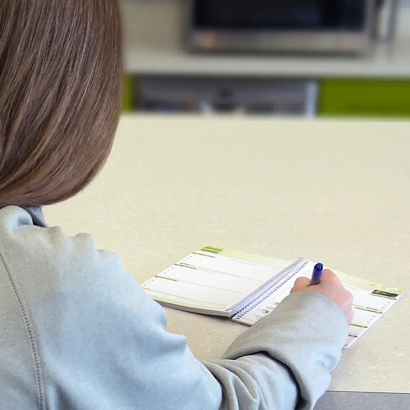  Female student fills out her planner on National Planner Day.