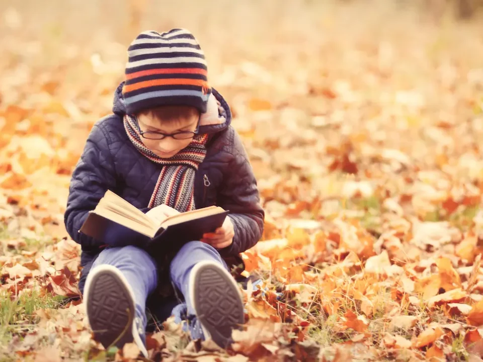 A young boy reads in the park for National Book Month.