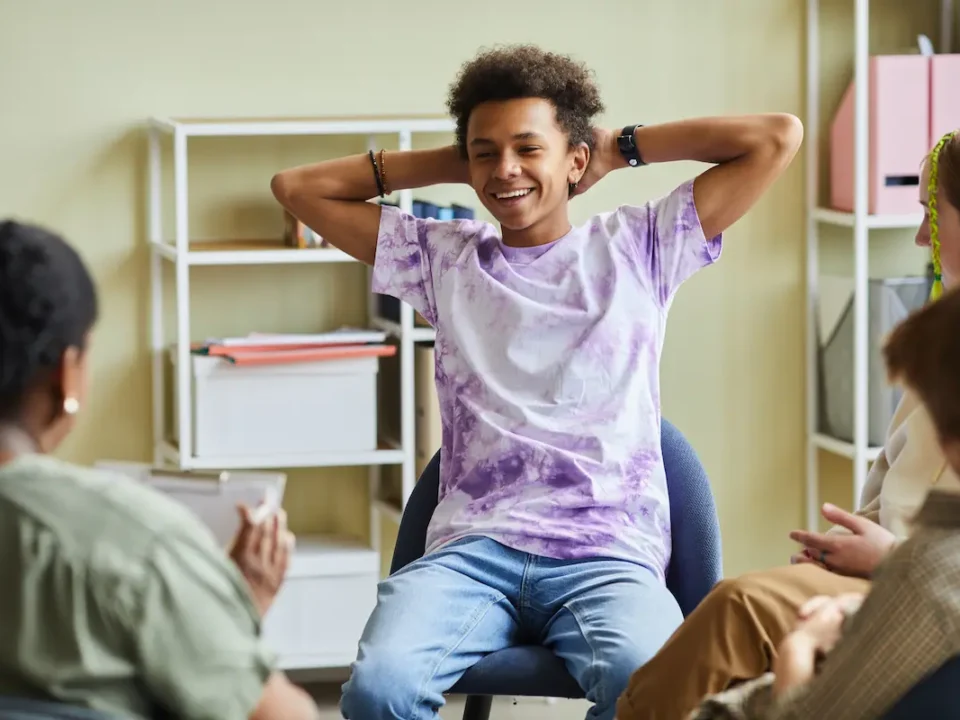 A teenager smiles in a group counseling session for good mental health.
