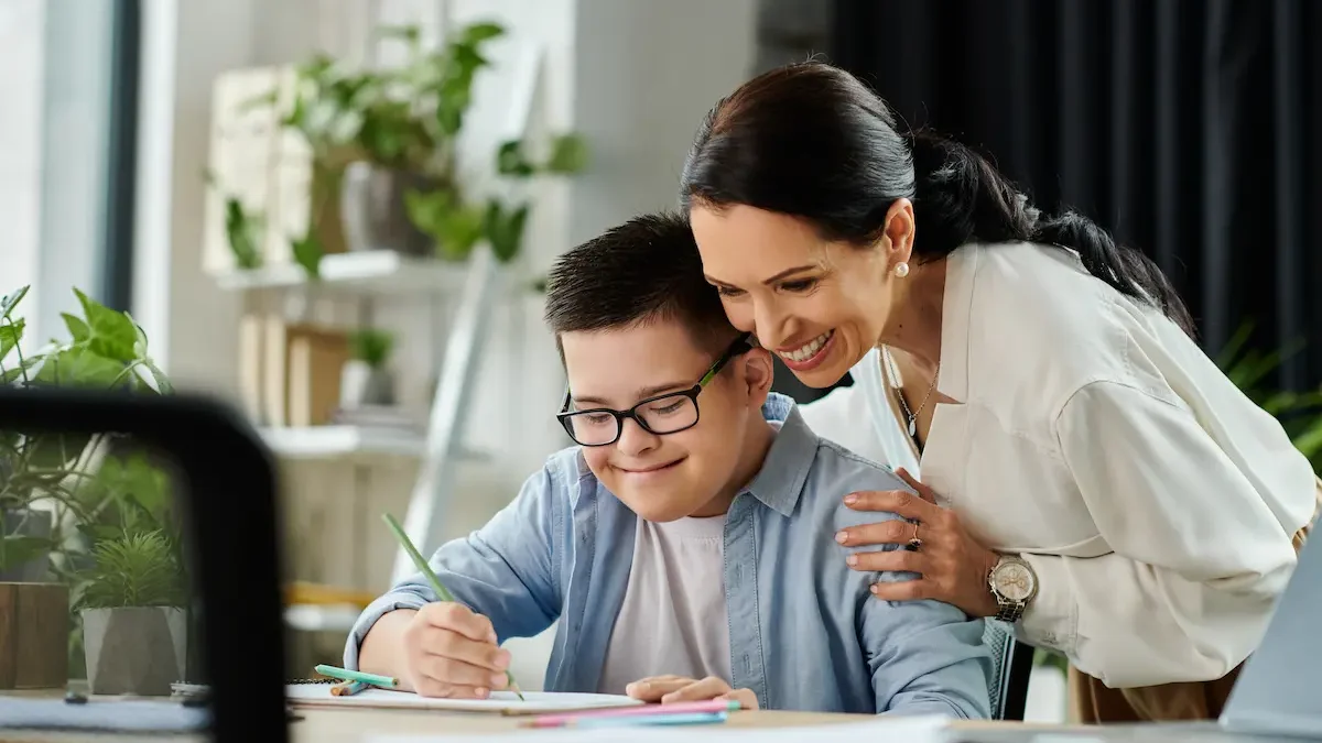 Teacher smiles as special needs student writes in datebook