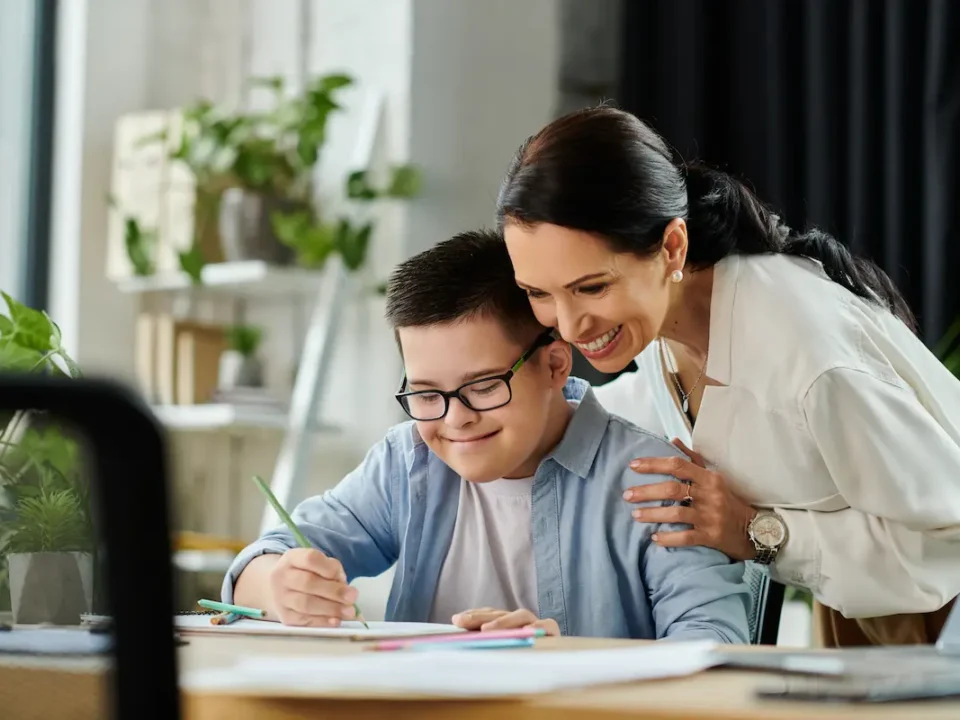 Teacher smiles as special needs student writes in datebook